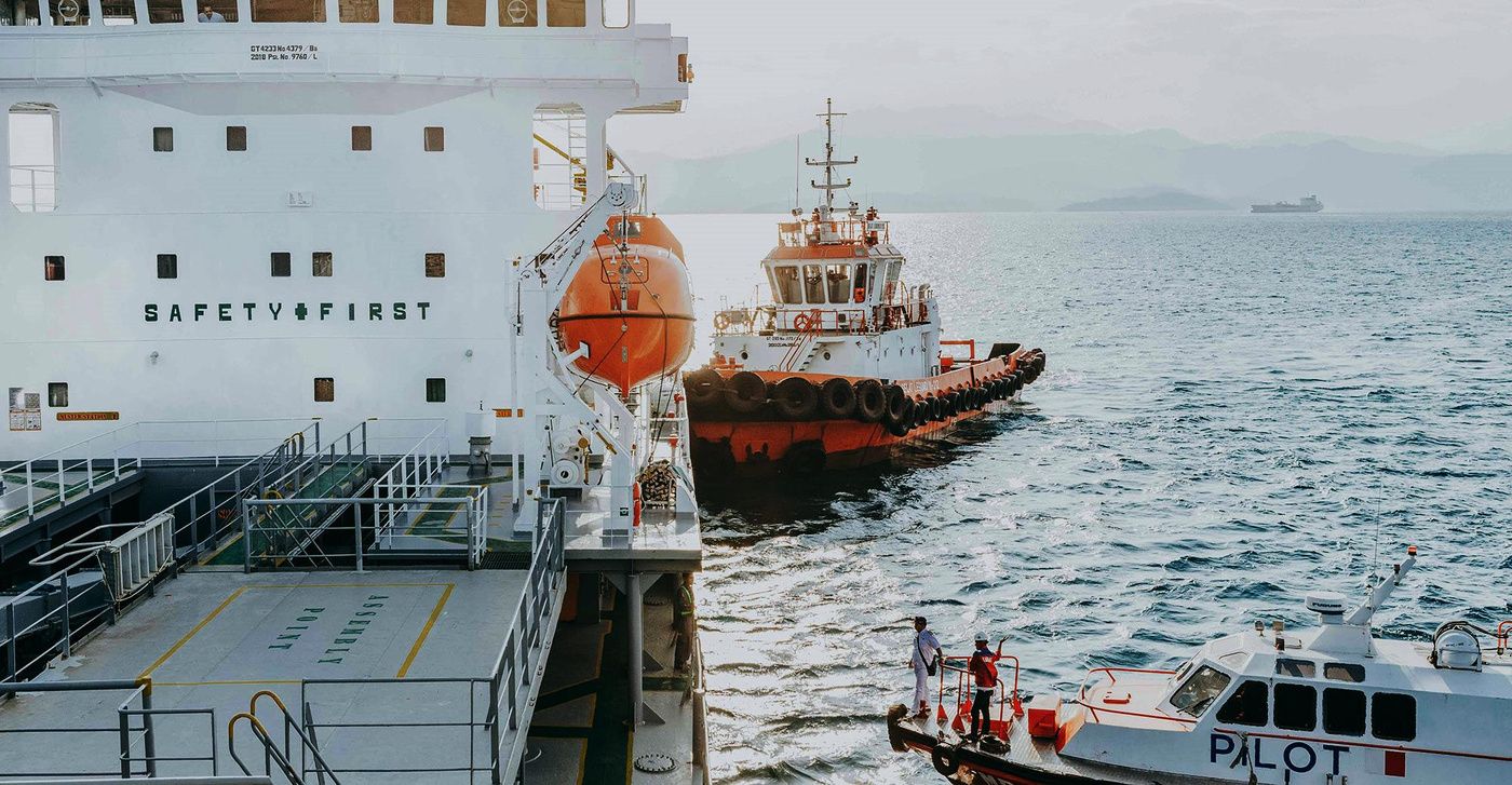 Tugboat and pilot vessel alongside a ship at sea